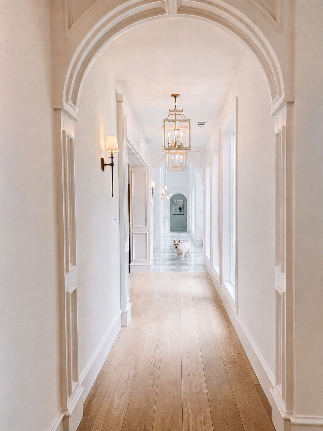 Light-filled arched hallway with detailed millwork, lantern lighting, and warm oak floors
